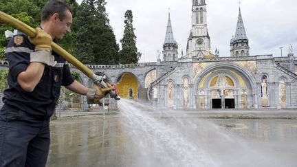 Un pompier en op&eacute;ration de nettoyage &agrave; Lourdes. Les sanctuaires ont &eacute;t&eacute; lourdement endommag&eacute;s par le d&eacute;bordement du Gave de Pau. (PASCAL PAVANI / AFP)