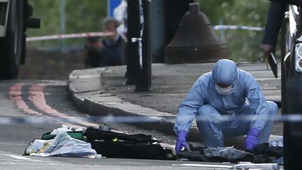 Un enqu&ecirc;teur de la police britannique relevant des indices sur les lieux de la violente attauqe durant laquelle deux hommes ont tu&eacute; un soldat &agrave; coup de machette, mercredi 22 mai &agrave; Londres (Royaume-Uni). (STEFAN WERMUTH / REUTERS)