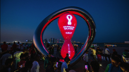 Une foule se rassemble pour prendre des photos près de l'horloge qui marque le compte à rebours avant la Coupe du monde à Doha au Qatar le 14 novembre 2022. (AFP)