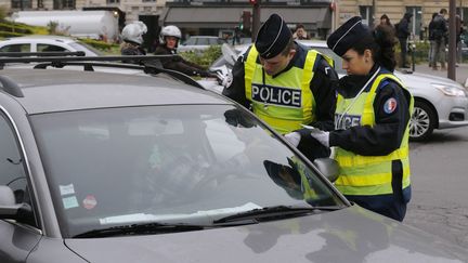 Des policiers contr&ocirc;lent une voiture, le 17 mars 2014 &agrave; Paris, alors qu'une mesure de circulation altern&eacute;e a &eacute;t&eacute; prise en raison d'un pic de pollution aux particules fines. (FRANCOIS GUILLOT / AFP)