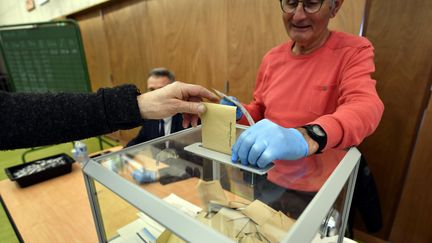 Un assesseur porte des gants dans un bureau de vote à Essey-lès-Nancy. (ALEXANDRE MARCHI / MAXPPP)