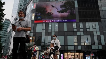 Des habitants&nbsp;chinois regardent un programme de télévision traitant des exercices militaires devant se tenir dans le détroit de Taïwan, à Pékin, le 4 août 2022.&nbsp; (NOEL CELIS / AFP)