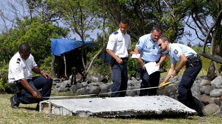 Des policiers inspectent un d&eacute;bris du vol MH370 retrouv&eacute; &agrave; La R&eacute;union, le 29 juillet 2015. (MAXPPP)