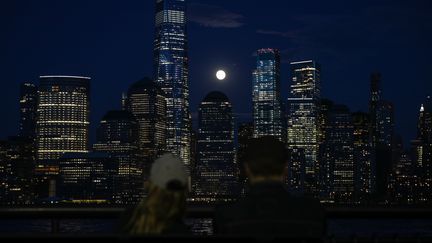 Deux personnes observent la "super Lune" à New York, le 7 avril, au terme d'une journée marquée par le sinistre record de près de 2 000 morts du Covid-19 aux Etats-Unis. (TAYFUN COSKUN / ANADOLU AGENCY / AFP)