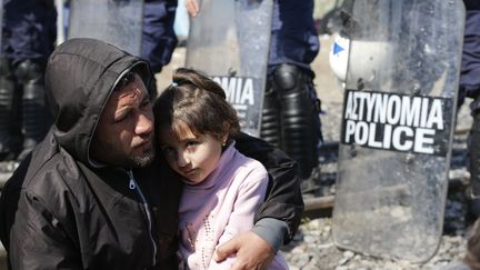 Un migrant tient sa fille dans ses bras devant un barrage de la police grecque, le 3 mars 2016.&nbsp; (MARKO DJURICA / REUTERS)