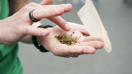 Une personne roule un joint en marge d'une manifestation pour la dépénalisation de l'usage du cannabis, à Paris, le 12 mai 2018. (MAGALI COHEN / HANS LUCAS / AFP)