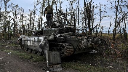 Cette photographie prise le 11 septembre 2022 montre un soldat ukrainien debout au sommet d'un char russe abandonné près d'un village à la périphérie d'Izioum, dans la région de Kharkiv, dans l'est de l'Ukraine. (JUAN BARRETO / AFP)