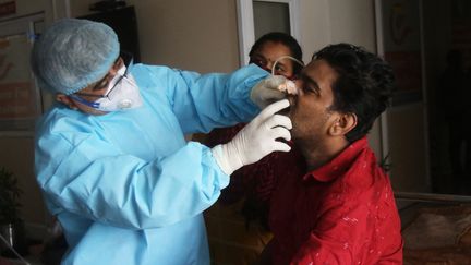 Un médecin indien examine la bouche d'un patient après une opération pour retirer une mucormycose dans un hôpital à Ghaziabad (Inde), le 3 juin 2021. (PANKAJ NANGIA / ANADOLU AGENCY / AFP)