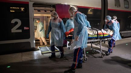 Le personnel médical transporte un patient infecté par le coronavirus dans un&nbsp;TGV médicalisé à la gare d'Austerlitz à Paris, avant son évacuation, avec 35 autres patients vers des hôpitaux de Bretagne, le 1er avril 2020. (THOMAS SAMSON / POOL)