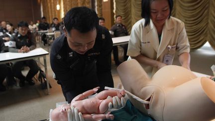 Un agent de circulation tha&iuml;landais apprend &agrave; r&eacute;aliser un accouchement en urgence sur un mannequin dans un h&ocirc;pital de Bangkok (ThaIlande), le 14 mars 2012. (CHAIWAT SUBPRASOM / REUTERS)