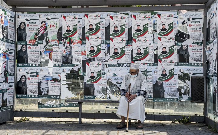 11 juin 2021, la veille des élections législatives en Algérie. Un vieil homme assis dans une station de bus, avec les affiches électorales du candidat du "Front du futur".&nbsp; (RYAD KRAMDI / AFP)