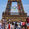 Des touristes se prennent en photo devant la tour Eiffel, à Paris, le 7 juin 2024. (J-F ROLLINGER / AFP)
