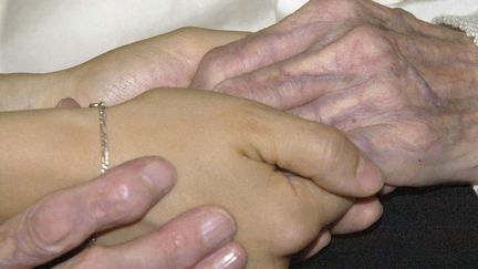 Les mains d'une personne agée et d'une jeune personne. Photo d'illustration. (MEHDI FEDOUACH / AFP)