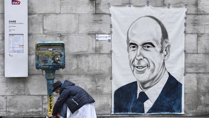 L'artiste Perez Roge, dit Rog, accroche un portrait de Valéry Giscard d'Estaing, le 9 décembre 2020, à Paris. (STEPHANE DE SAKUTIN / AFP)