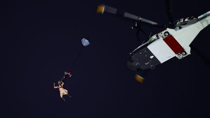 Tiens, la reine arrive au stade en parachute. Ne vous inqui&eacute;tez pas pour elle, James Bond la suit de pr&egrave;s pour la prot&eacute;ger... (OLIVIER MORIN / AFP)