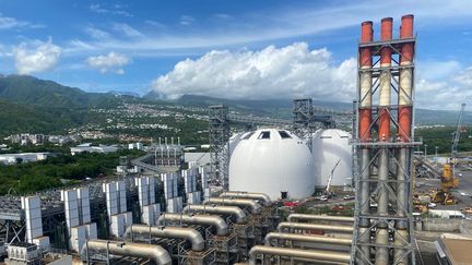 L'une des cheminées et les tuyaux des moteurs de la centrale EDF de Port-Est (au premier plan). Et les dômes blancs construits par l'entreprise Albioma pour stocker ses granulés de bois (en arrière plan). (LAURIANE DELANOE / RADIOFRANCE)