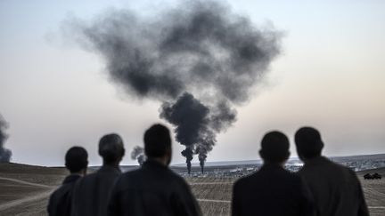 Des hommes observent les combats dans la ville de Kobani, en Syrie, le 26 octobre 2014. (BULENT KILIC / AFP)