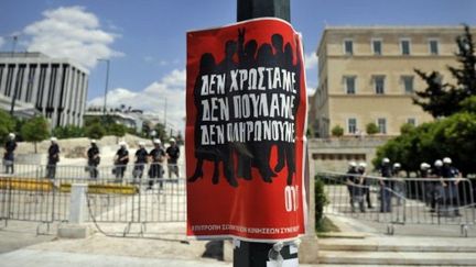 Policiers protégeant le Parlement à Athènes; au 1er plan, une affiche de protestation contre les mesures d'austérité (AFP - LOUISA GOULIAMAKI)