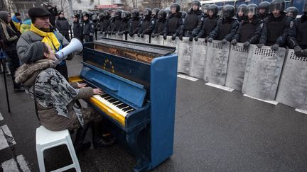 Des manifestants chantent et jouent du piano devant les forces de l'ordre qui prot&egrave;gent l'immeuble pr&eacute;sidentiel &agrave; Kiev (Ukraine), le 7 d&eacute;cembre 2013. (REUTERS)