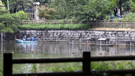 Des policiers fouillent une mare dans un parc de Tokyo après la découverte de morceaux d'un corps humain, jeudi 23 juin 2016.&nbsp; (JIJI PRESS / AFP)