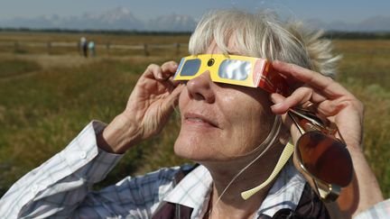 Une femme regarde à travers des lunettes de protection à la veille d'une éclipse totale de soleil, le 20 août 2017 à Jackson (Etats-Unis). (GEORGE FREY / GETTY IMAGES NORTH AMERICA / AFP)