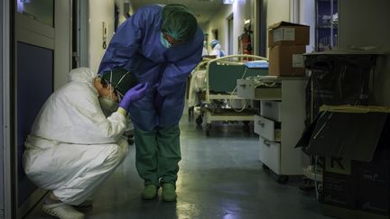 Une infirmière réconforte une de ses collègues, épuisée, le 13 mars 2020 à l'hôpital de Crémone, au sud-est de Milan (Italie). Afin de contenir l'épidémie de Covid-19, un confinement strict a été imposé à la population de la région quatre jours plus tôt. (PAOLO MIRANDA / AFP)