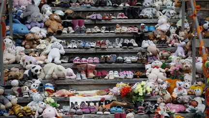 Des chaussures d'enfants et des peluches, déposés en hommage aux enfants indigènes arrachés à leur famille sur les marches de l'ancien pensionnat Mohawk Institute, à Brantford (Ontario, Canada), le 9 novembre 2021. (COLE BURSTON / AFP)