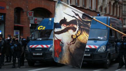 Drapeau à l'effigie de la Révolution française&nbsp;et gendarmes mobiles, lors de la manifestation contre la précarité&nbsp;et la réforme de l'assurance chômage&nbsp;du samedi 5 décembre&nbsp;2020 à Toulouse.&nbsp;&nbsp; (SANDRA FASTRE / HANS LUCAS / AFP)