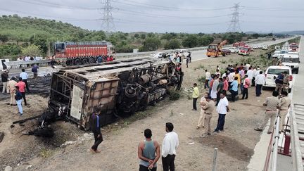 People in front of the bus which had an accident and caught fire on July 1, 2023 in Sindkhed Raja, in the Indian state of Maharashtra.  (GAJANAN MEHETRE / AFP)