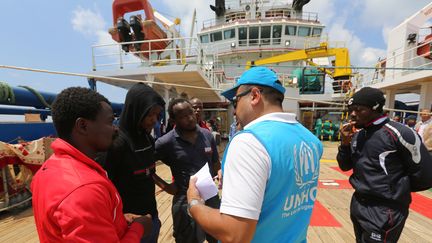 Des migrants africains avec un responsable du HCR à bord du navire "Sarost 5" amarré dans le port de Zarzis, dans le sud de la Tunisie, le 1er août 2018. (FATHI NASRI / AFP)