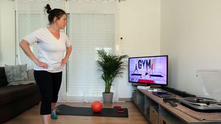 Une jeune femme confinée suit les cours de sport à la télévision. Photo d'illustration. (MAXPPP)