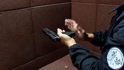 Un policier parisien vérifiant son arme de service, le 19 octobre 2017. (STEPHANE DE SAKUTIN / AFP)