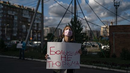 Une femme tient une pancarte où l'on peut lire en russe "un hôpital n'est pas une prison", devant l'hôpital d'Omsk où a été admis l'opposant Alexeï Navalny après des soupçons d'empoisonnement.&nbsp; (DIMITAR DILKOFF / AFP)