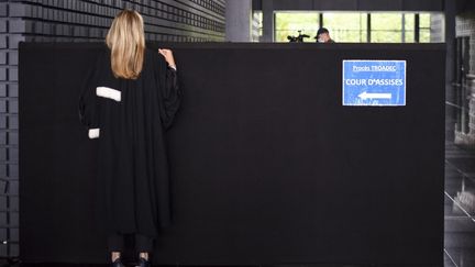 Une avocate regarde par dessus un panneau indiquant le chemin de la cour d'assises au palais de justice de Nantes, le 23 juin 2021, au deuxième jour du procès de l'affaire Troadec.&nbsp; (SEBASTIEN SALOM-GOMIS / AFP)