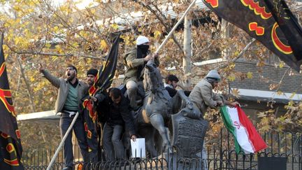 Des manifestants brandissent des drapeaux rendant hommage &agrave; l'imam Hussein, petit-fils de Mahomet, sur les grilles de l'ambassade britannique &agrave; T&eacute;h&eacute;ran (Iran), le 29 novembre 2011. (ATTA KENARE / AFP)