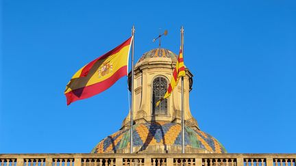 Le drapeau national espagnol (gauche) et le drapeau régional catalan (droite) flottent au-dessus du Palais de la Generalitat, lundi 30 octobre,&nbsp;première journée d'administration directe de la région par Madrid. (MAXPPP)