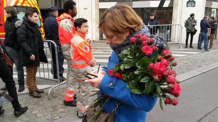 Une femme rend hommage aux victimes de l'attaque contre "Charlie Hebdo" devant les locaux du journal, &agrave; Paris, le 7 janvier 2015. (FABIEN MAGNENOU / FRANCETV INFO)