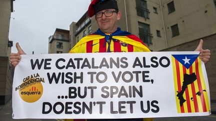 Le vote &eacute;cossais a &eacute;t&eacute; suivi de pr&egrave;s dans la r&eacute;gion de Barcelone, &eacute;galement tent&eacute;e par la s&eacute;cession. Ce Catalan avait fait le d&eacute;placement &agrave; Edimbourg pour brandir une pancarte devant le Parlement &eacute;cossais : "Nous, Catalans, souhaitons aussi voter ... mais l'Espagne refuse" (18 septembre 2014). (LESLEY MARTIN / AFP)