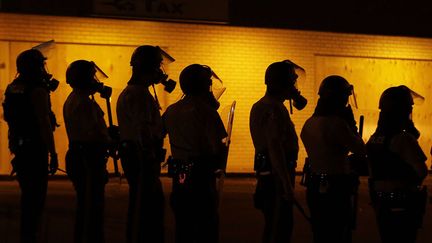 Des policiers patientent apr&egrave;s avoir envoy&eacute; du gaz lacrymog&egrave;ne pour disperser la foule lors d'un hommage &agrave; Michael Brown &agrave; Ferguson (Missouri, Etats-Unis, le 17 ao&ucirc;t 2014. (CHARLIE RIEDEL / AP / SIPA)