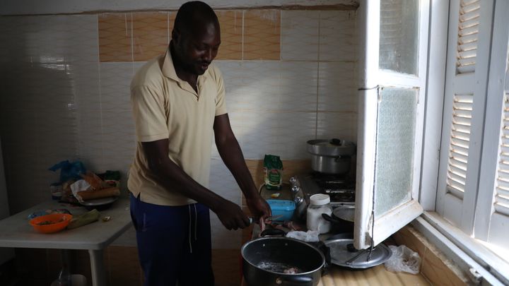 Christian prépare un bœuf sauce arachide, une recette camerounaise, dans la cuisine de son logement à Sfax (Tunisie), en août 2023. (ELISE LAMBERT / FRANCEINFO)