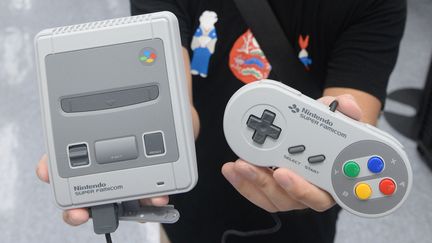 Un homme présente une&nbsp;Super Nintendo&nbsp;Mini à&nbsp;Osaka (Japon), le 5 octobre 2017. (TAKAYUKI HAMAI / YOMIURI / AFP)