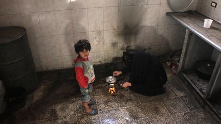 Une femme syrienne cuisine de la poudre de riz dans sa cuisine à Douma, une ville de la Ghouta orientale, en novembre 2017. (HAMZA AL-AJWEH / AFP)