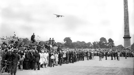 Le jour apr&egrave;s la Lib&eacute;ration de Paris.&nbsp;Un avion survole la foule lors de la parade militaire sur la place de la Concorde, le 26 ao&ucirc;t 1944.&nbsp; (STRINGER / AFP)