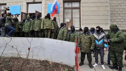 Des hommes masqu&eacute;s brandissent des drapeaux russes devant l'entr&eacute;e bloqu&eacute;e d'un immeuble syndical, &agrave; Simferopol (Ukraine), le 1er mars 2014. (GENYA SAVILOV / AFP)