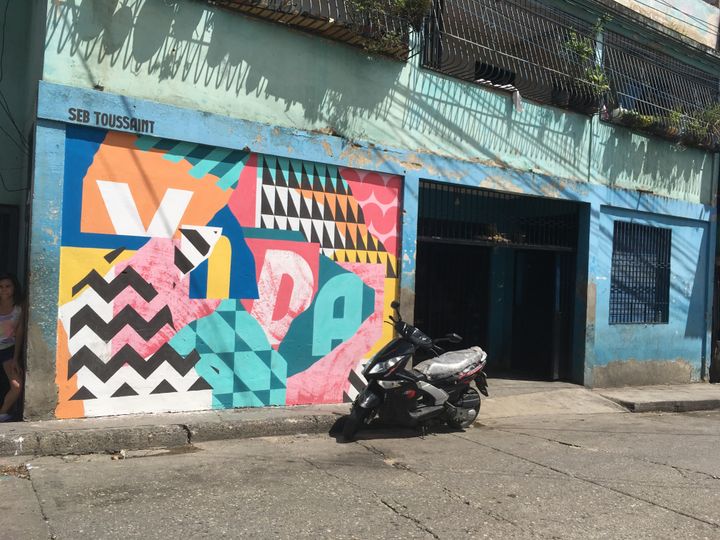 L'artiste franco-britannique Seb Toussaint a animé les rues de Petare au Venezuela de fresques colorées qui cache un mot choisi par un habitant.&nbsp;Sur l’épicerie du quartier, c’est le mot "Vida", (vie). (BENJAMIN DELILLE / RADIO FRANCE)