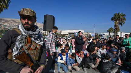 Un rebelle se tient en marge de la foule à Damas (Syrie), le 15 décembre 2024. (LOUAI BESHARA / AFP)