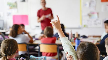 Dans une classe d'école primaire, une élève lève la main pour répondre à une question de l'enseignant, le 22 juin 2023, à Saumur (Maine-et-Loire). (FREDERIC PETRY / HANS LUCAS)