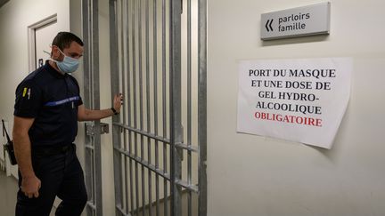 Un gardien de prison portant un masque de protection ouvre la porte d'un couloir menant au parloir de la prison de la Santé, à Paris, en novembre 2020. (BERTRAND GUAY / AFP)