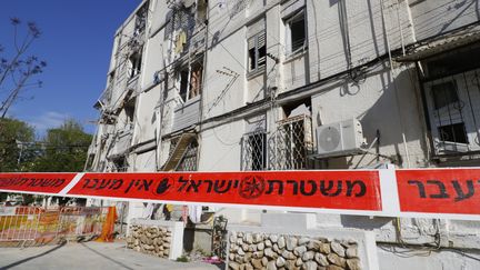 Un cordon de sécurité installé autour d'un immeuble détruit par une roquette palestinienne, dans la ville israélienne d'Ashkelon, près de la bande de Gaza. (JACK GUEZ / AFP)