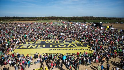 Des manifestants rassemblés à Hambach (Allemagne), le 6 octobre 2018, pour fêter le sauvetage provisoire d'une forêt menacée de déboisement par l'industrie du charbon. (CHRISTOPHE GATEAU / DPA / AFP)